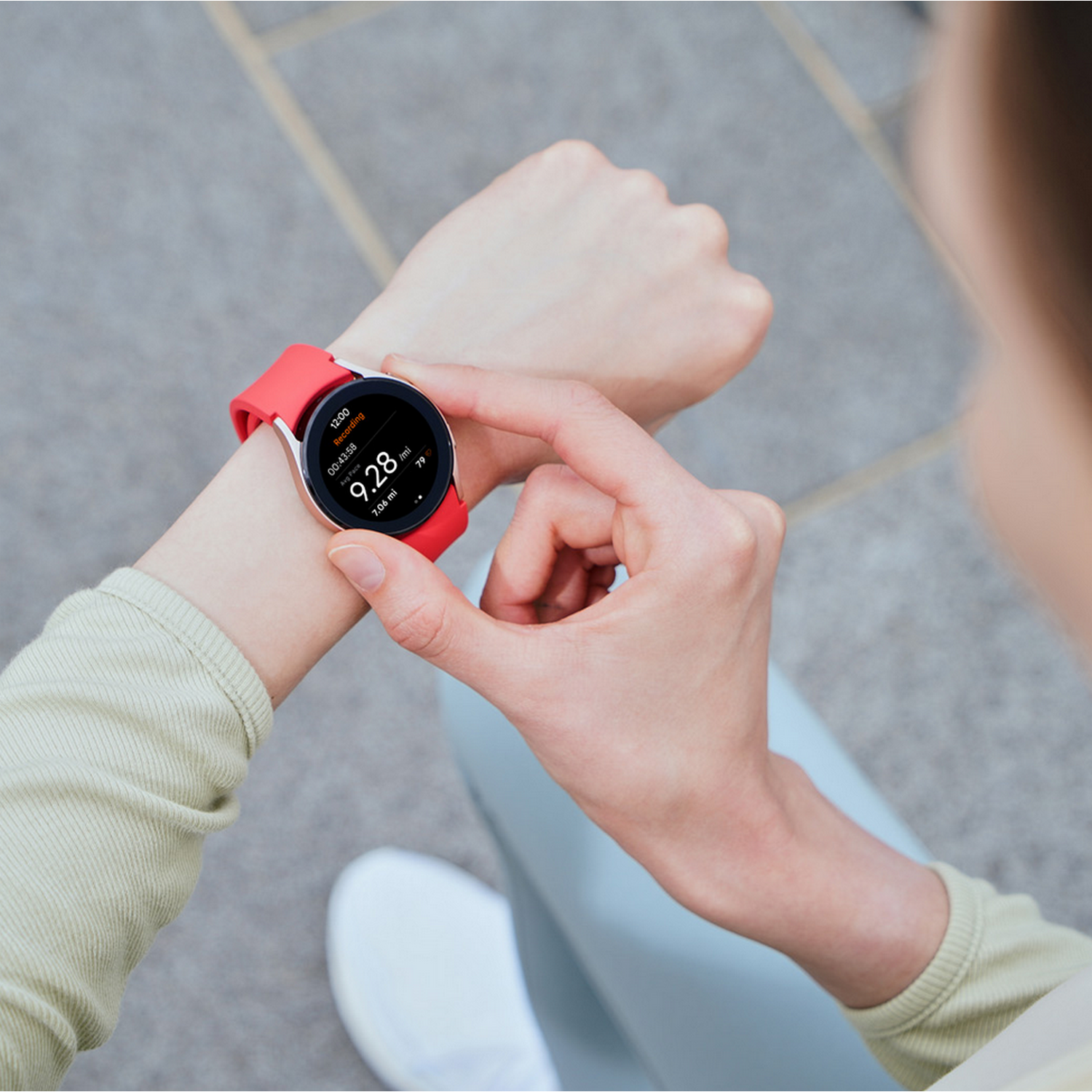 Persoon met een smartwatch met rode band. Het horloge toont tijd, hartslag en activiteit statistieken.