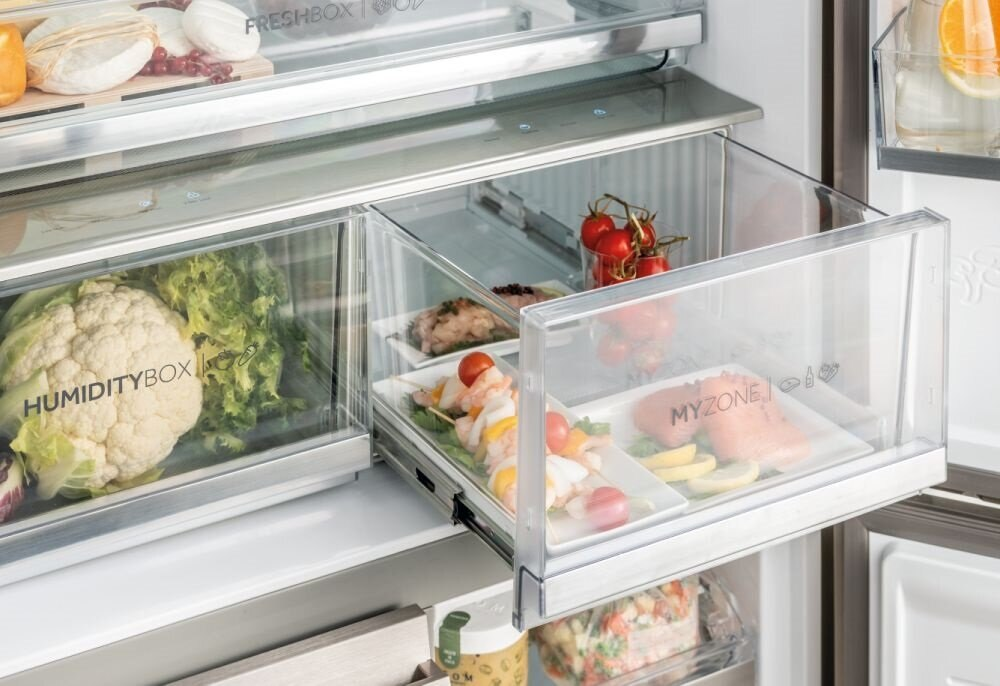 Szuflady lodówki z warzywami, gotowymi potrawami i widocznymi, oznakowanymi przegródkami.