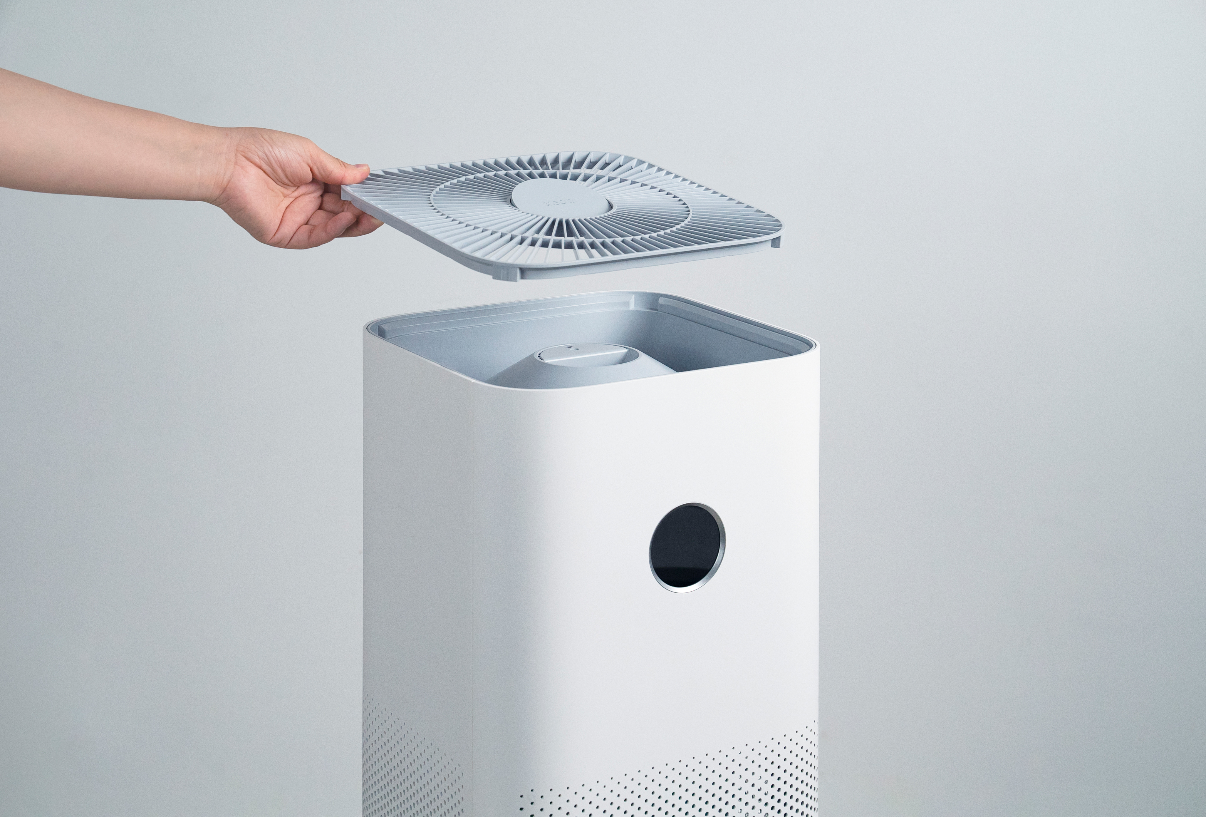 El, beyaz bir hava temizleyiciye hava filtresi yerleştiriyor.