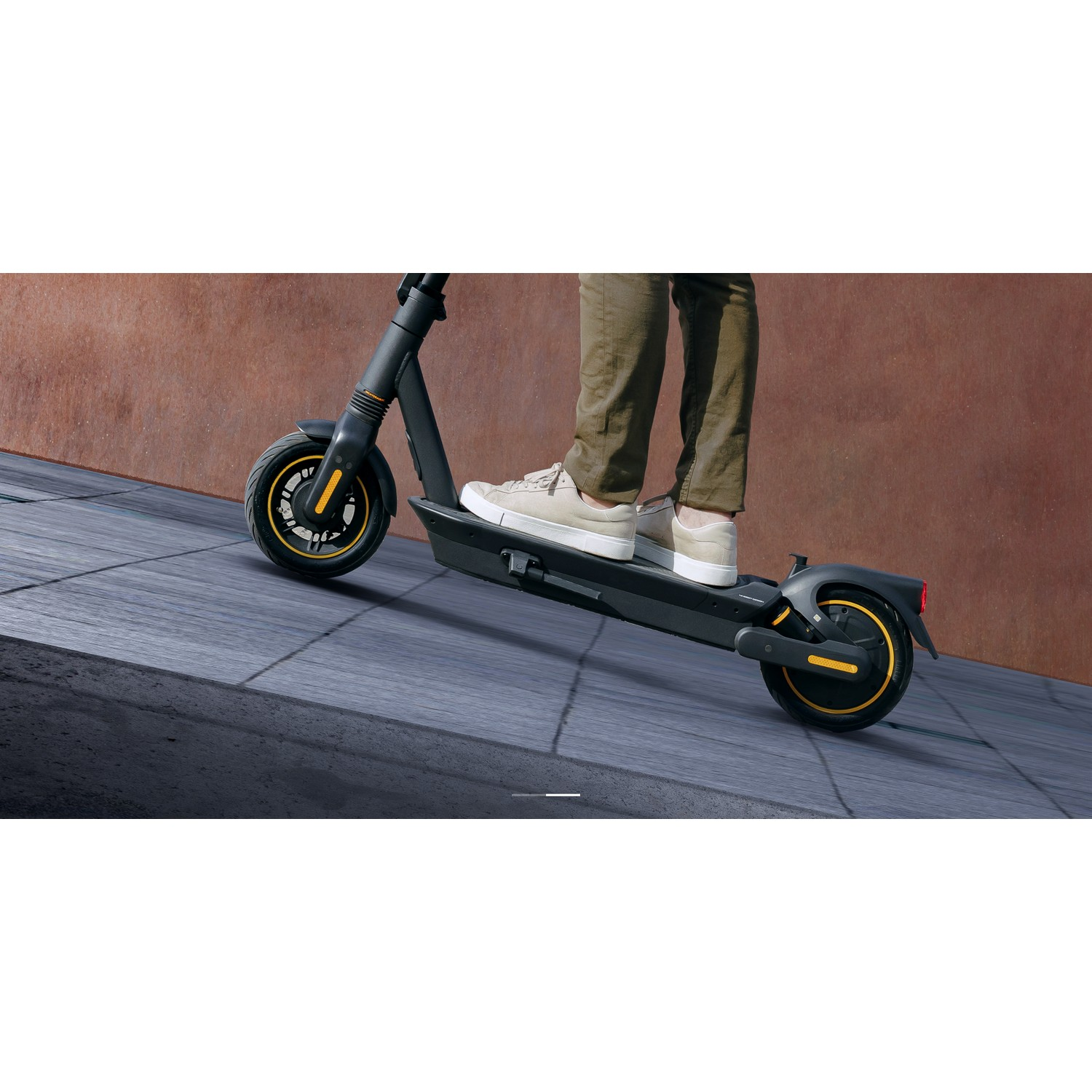 Une personne conduit une trottinette électrique noire et jaune sur une surface pavée.