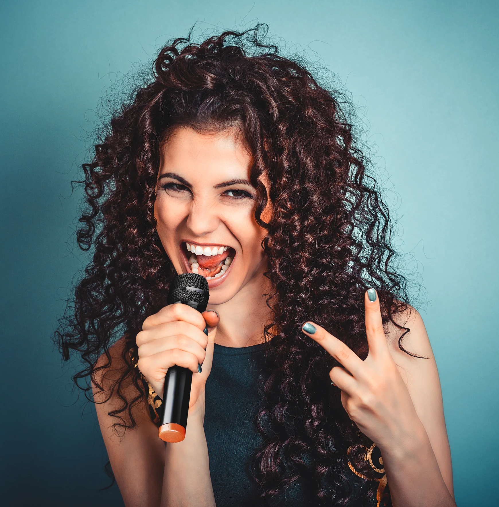 Eine Frau mit lockigem Haar singt in ein Mikrofon, Friedenszeichen.