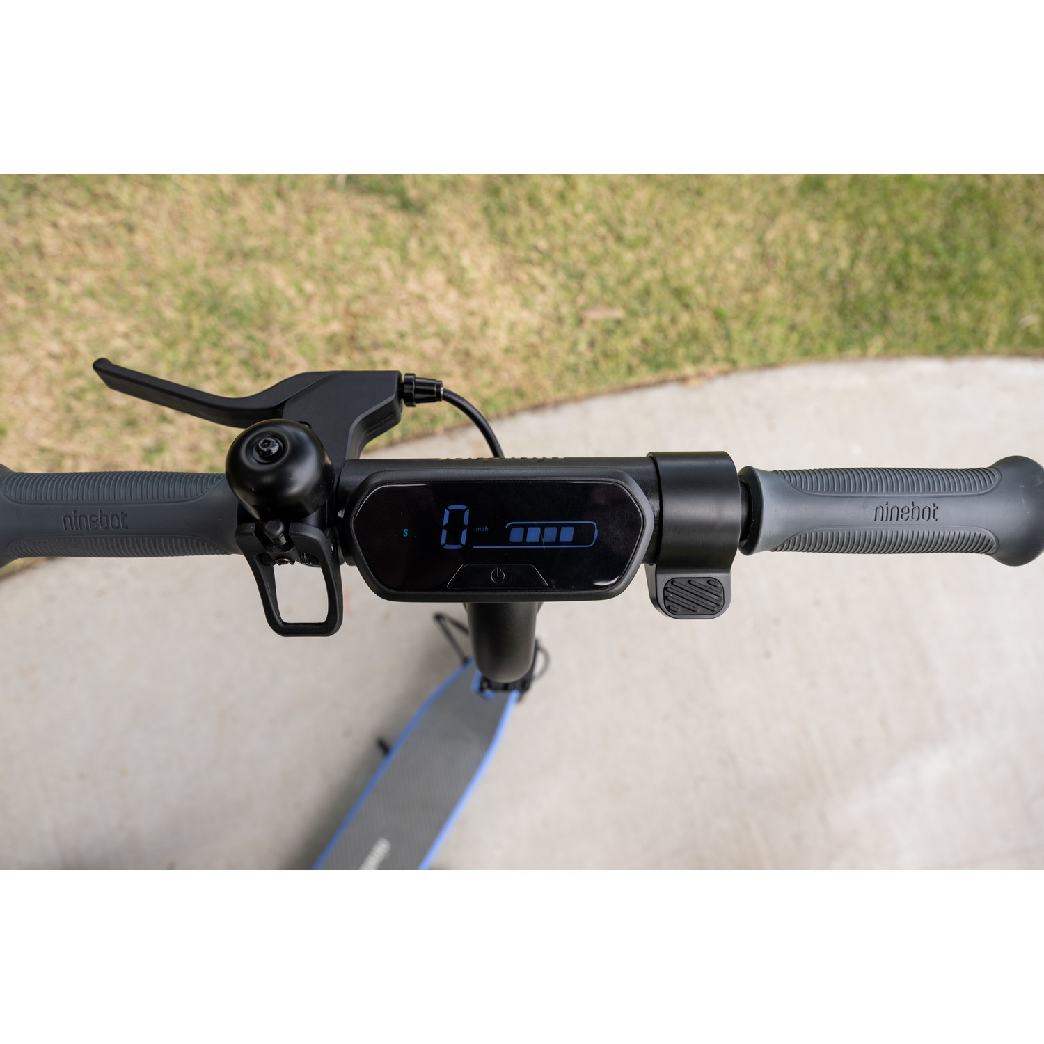Stuur van de scooter met snelheid, batterij en bel. Op de stoep.