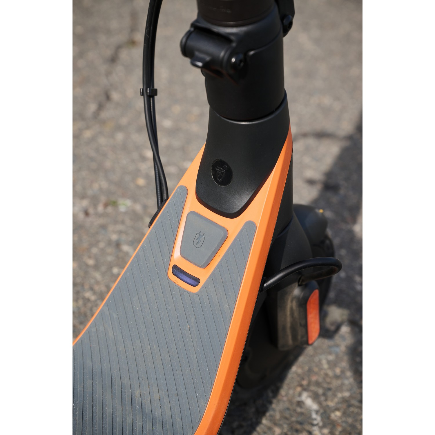 Close-up van de voorkant van een elektrische scooter, met het dek en de stuurkolom.