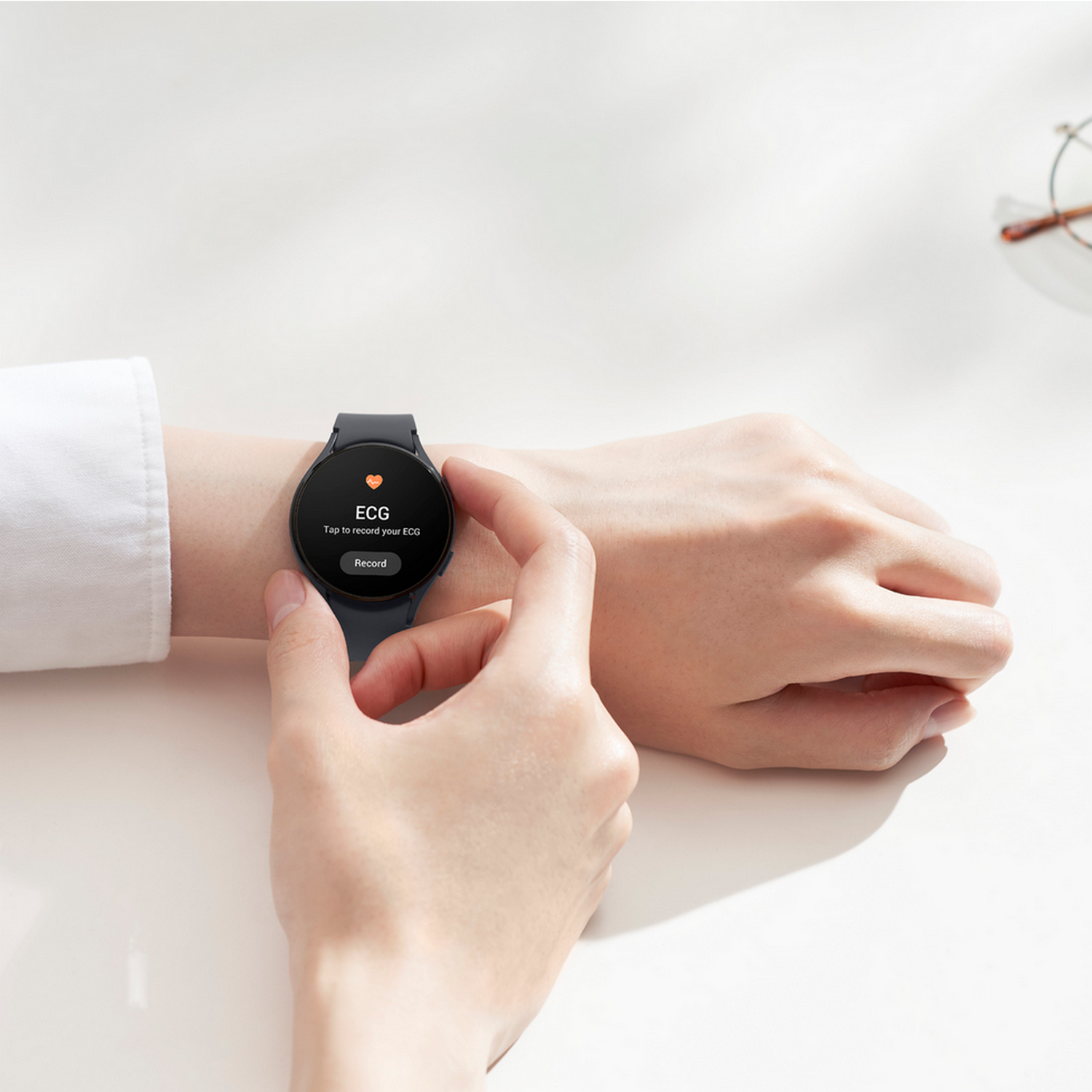 De pols van een persoon met een zwarte smartwatch die een ECG-scherm toont.