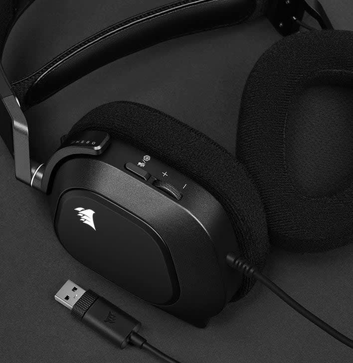 Fekete gamer fejhallgató sötét felületen. Mikrofon és hangerőszabályzó is van rajta.