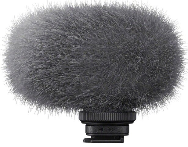 Szara osłona mikrofonu z puszystą, futrzaną teksturą, zamontowana na czarnej podstawie.