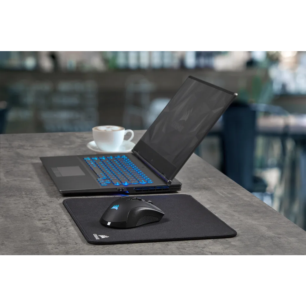 Egy laptop, egér és egérpad egy asztalon egy csésze kávéval.