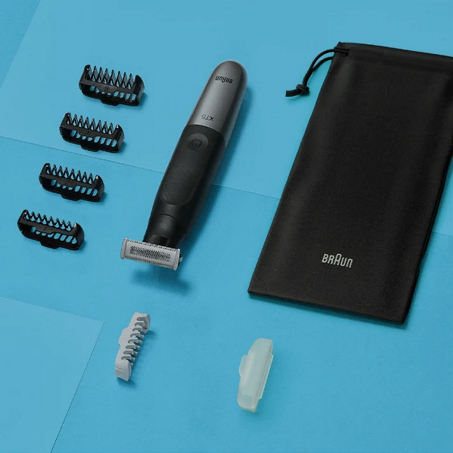 Une tondeuse Braun X15 noire avec accessoires et une pochette noire sur une surface bleue.
