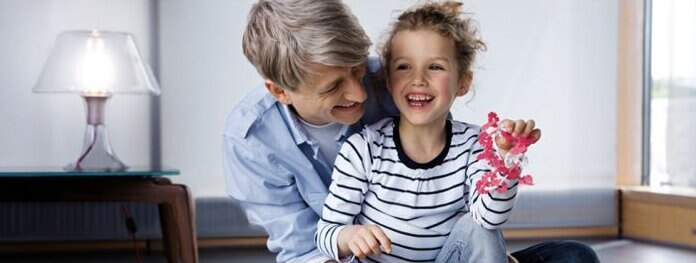 Dziadek i uśmiechnięta dziewczynka, dziewczynka trzyma zabawkę, i lampę.