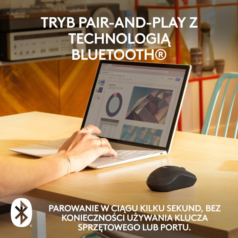 Laptop na drewnianym stole z myszą. Osoba pisze na klawiaturze.