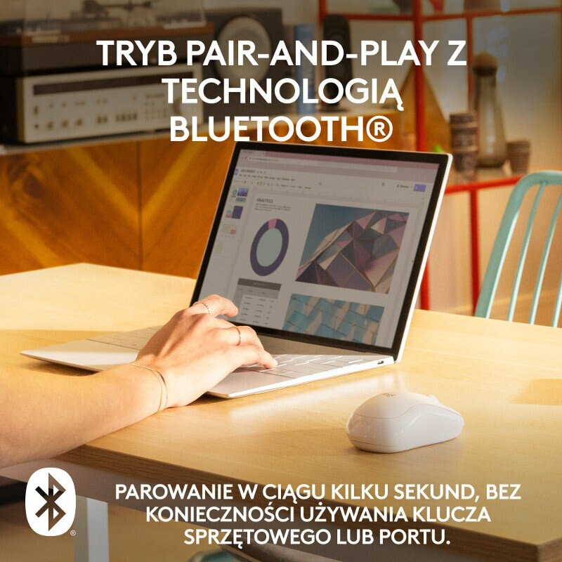 Osoba używająca laptopa i białej myszy na drewnianym stole. Pokazano logo Bluetooth.