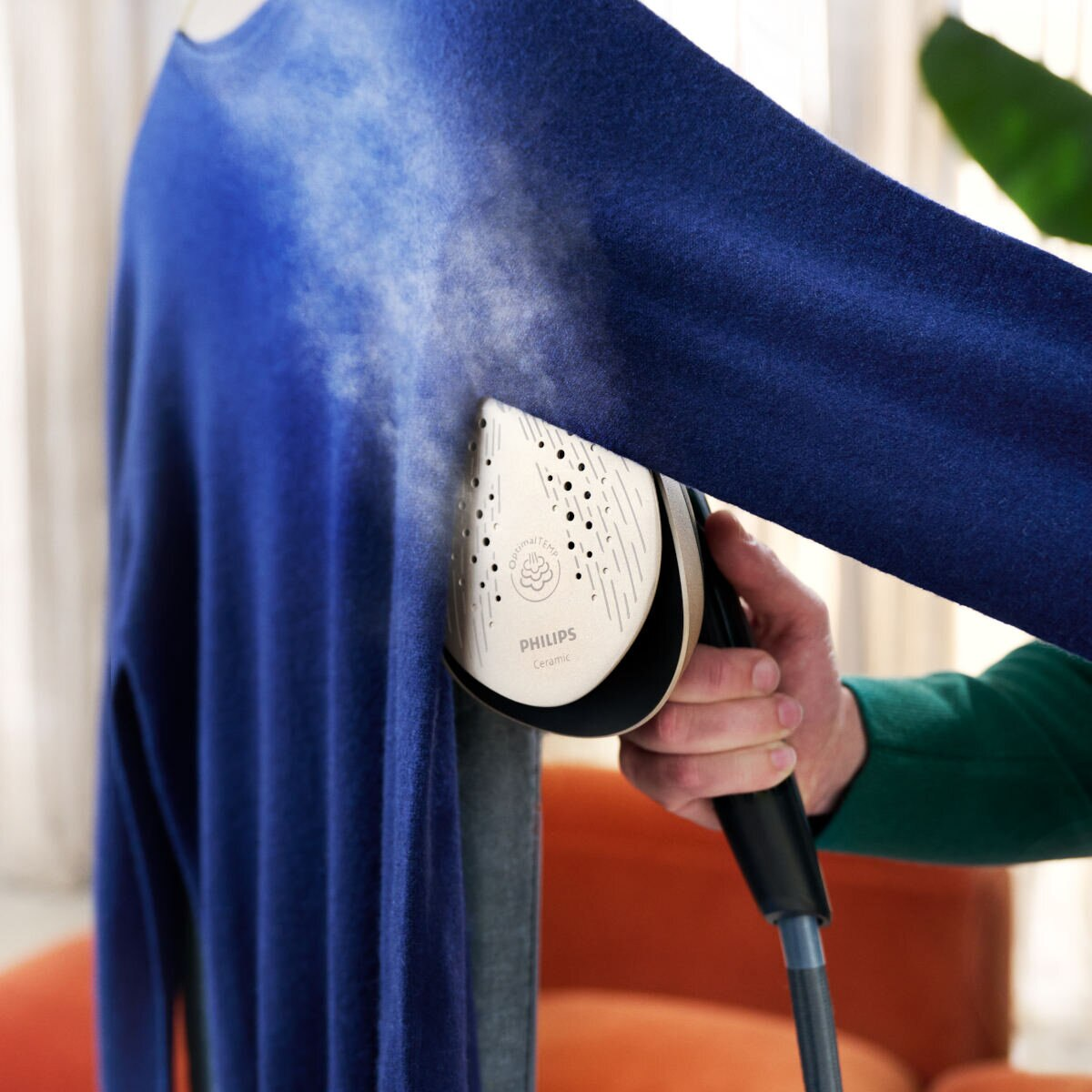 Niebieski sweter jest prasowany parą za pomocą żelazka ceramicznego Philips.