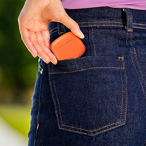 La mano de una mujer sostiene un estuche de auriculares inalámbricos naranja en el bolsillo trasero de sus jeans.