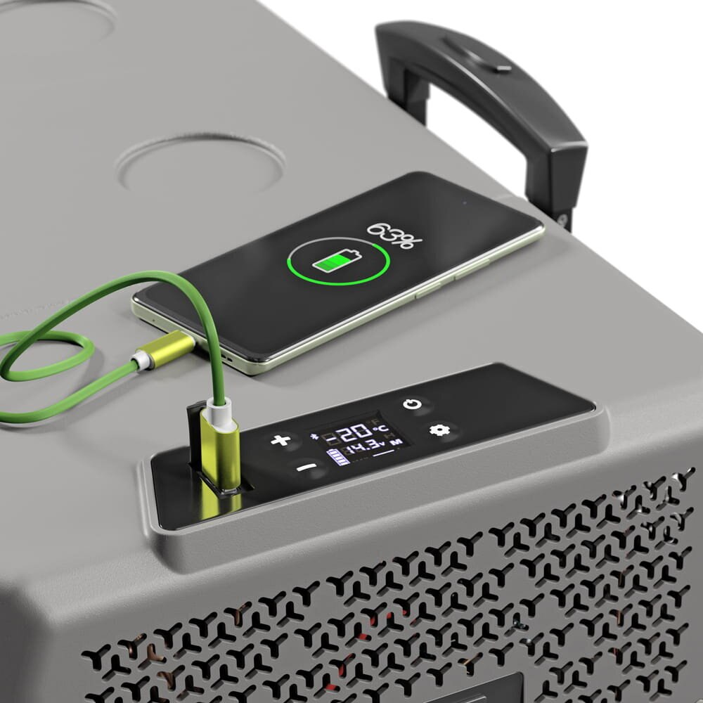 Smartfon ładuje się zielonym kablem na wyświetlaczu szarej lodówki.