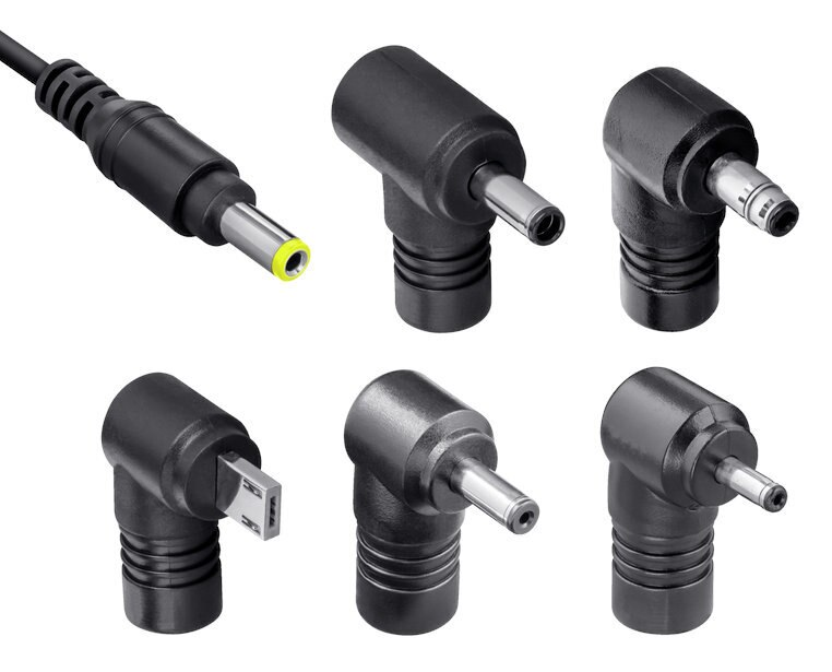 Kilka czarnych zasilaczy z różnymi typami złączy na białym tle.
