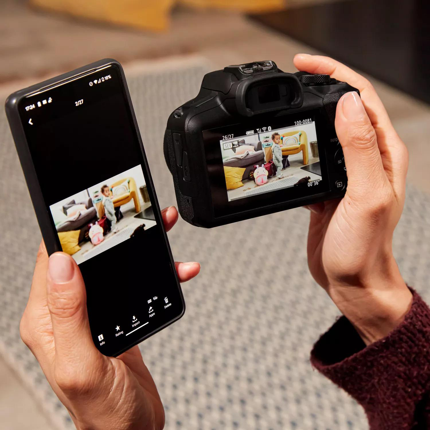 Eine Person hält ein Smartphone und eine Kamera. Das Telefon zeigt ein Foto, das auch auf dem Kamerabildschirm ist.