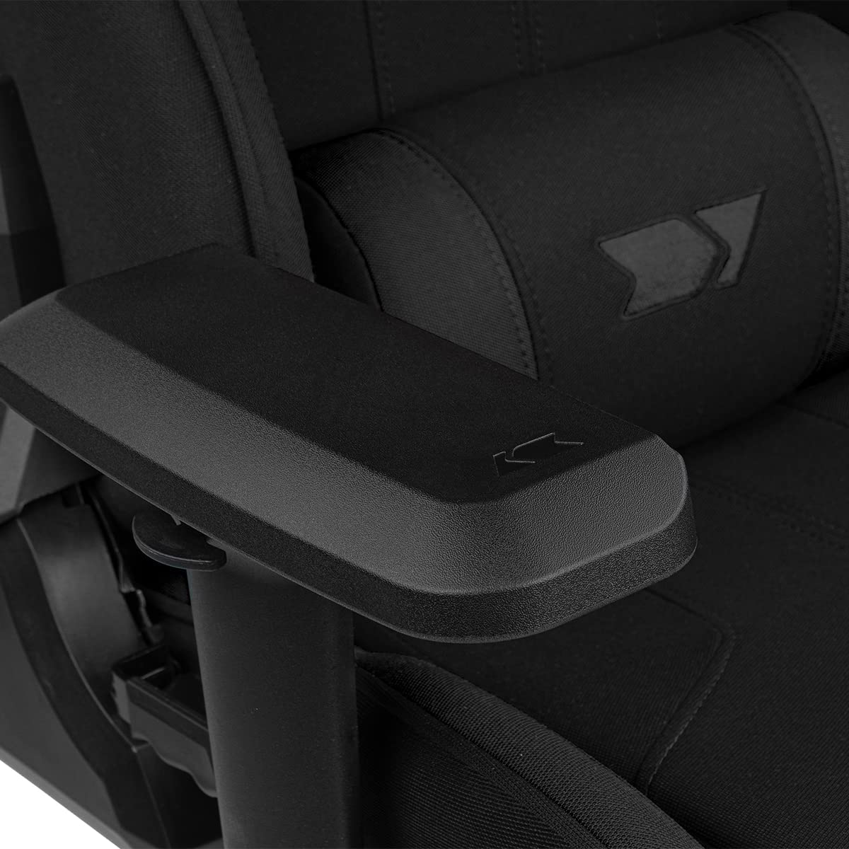 Detalle del reposabrazos de la silla gamer negra, mostrando costuras y logo.