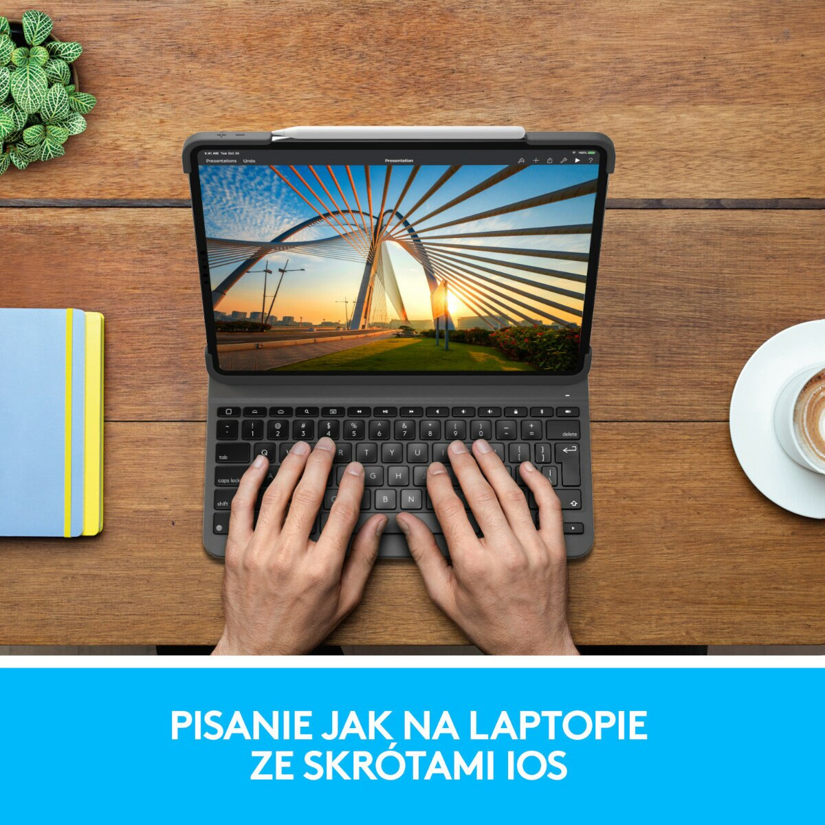 Ręce piszące na klawiaturze podłączonej do tabletu. Notatnik i filiżanka kawy są na drewnianej powierzchni.