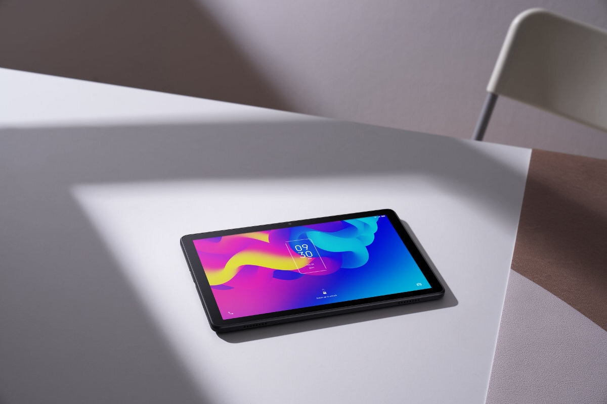 Tablet na białym stole. Ekran wyświetla kolorowy, abstrakcyjny wzór.