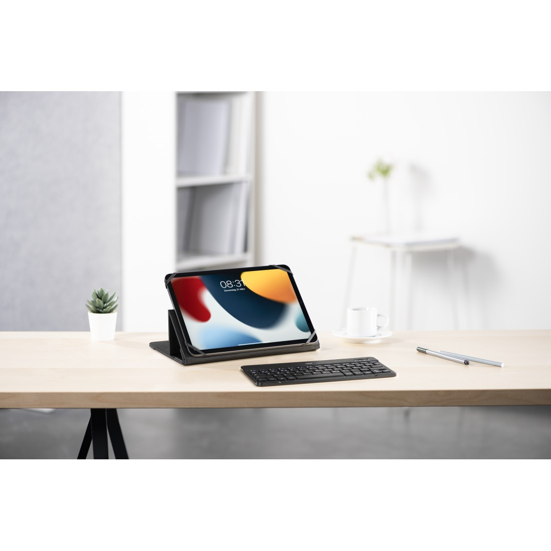 Tablet und Tastatur auf einem Holztisch, Pflanze und Kaffeetasse sind auf dem Tisch.