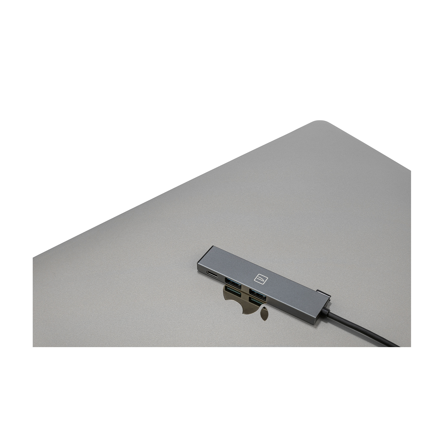 Un laptop grigio con un hub USB collegato, su una superficie bianca.