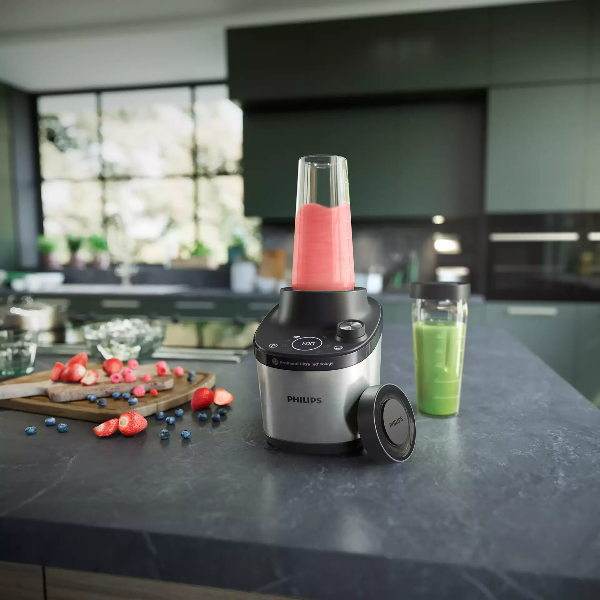 Turmixgép gyümölccsel és egy smoothie-s pohárral. A turmixgép ezüst, a gyümölcsök fa deszkán.