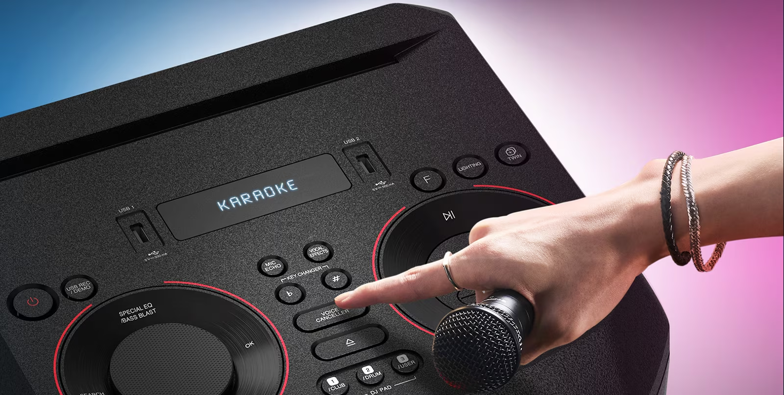 Egy kéz egy gombot nyom egy fekete hangszórón. A képernyőn a KARAOKE felirat látható.