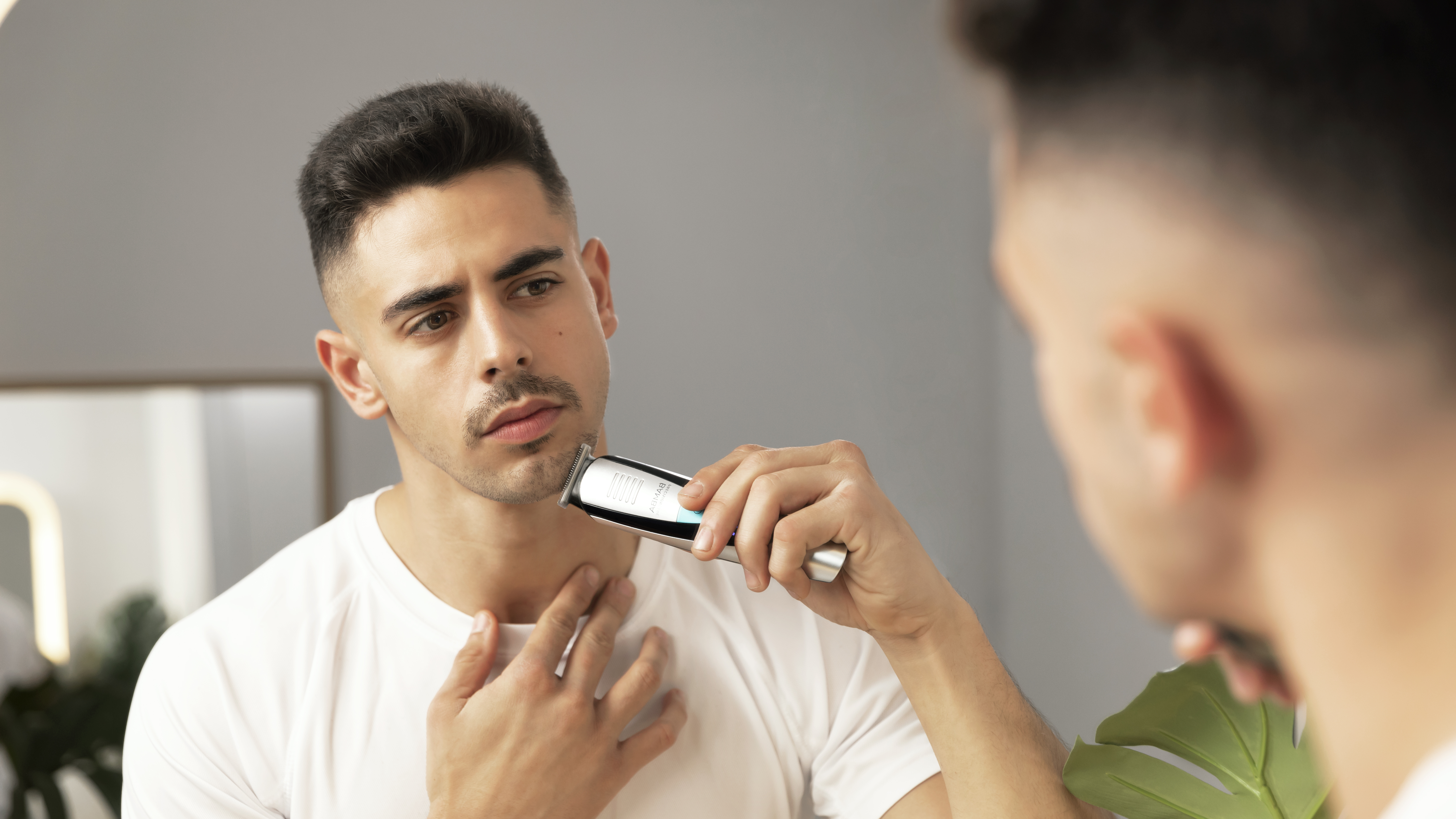 Primer plano de un hombre recortando su barba con una recortadora plateada y negra.
