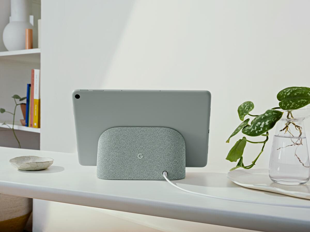 Ein graues Tablet ist auf einer grauen Lautsprecherbasis montiert. Ein weißes Kabel verbindet die Basis.