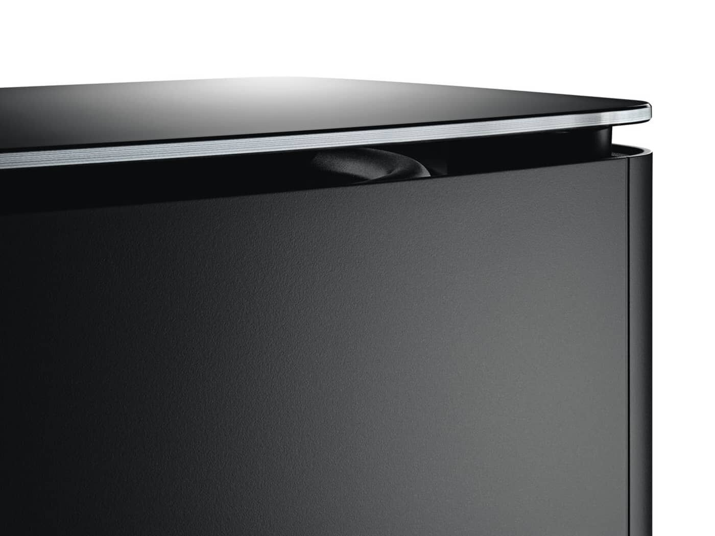 Czarny głośnik ze srebrnym wykończeniem i czarnym otworem na górze.