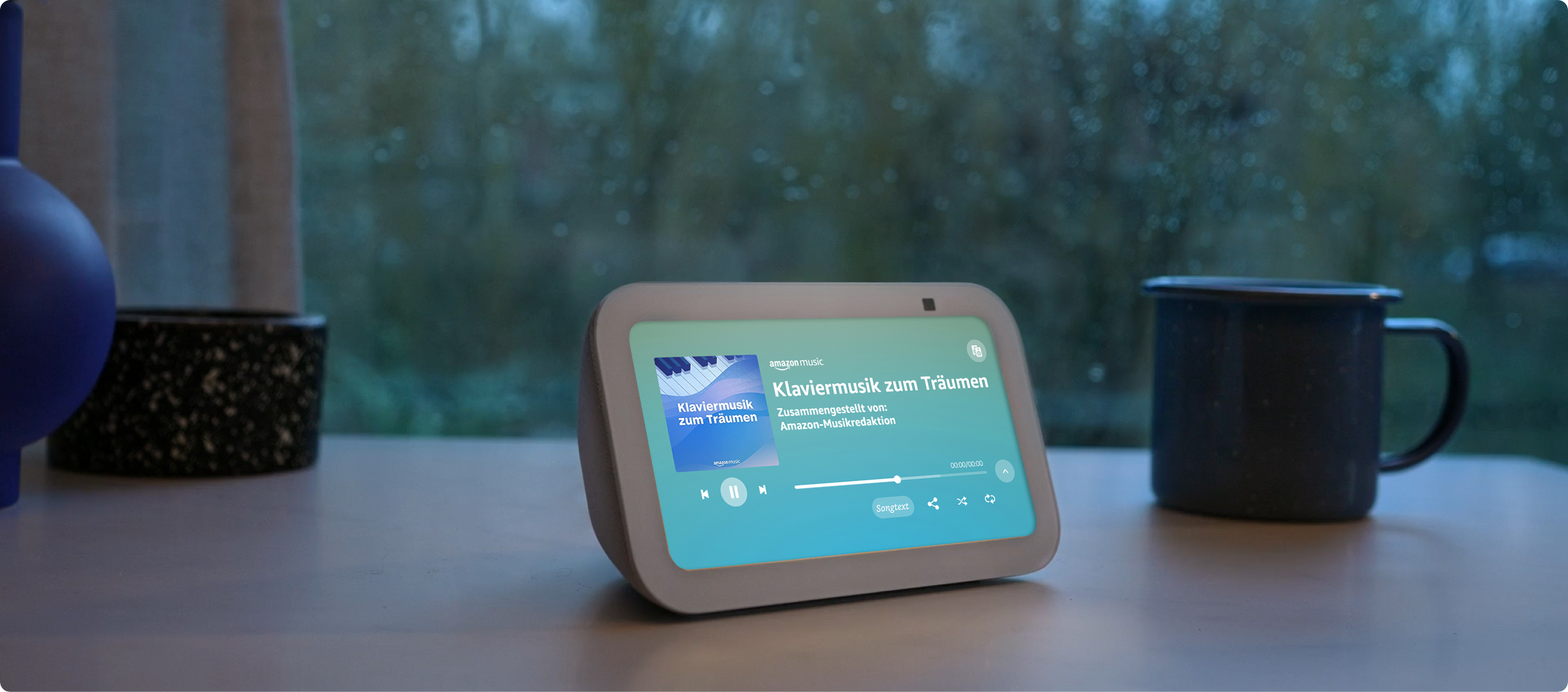 Smart Display auf einem Tisch, zeigt eine Musikoberfläche. Hintergrund ist ein Fenster.