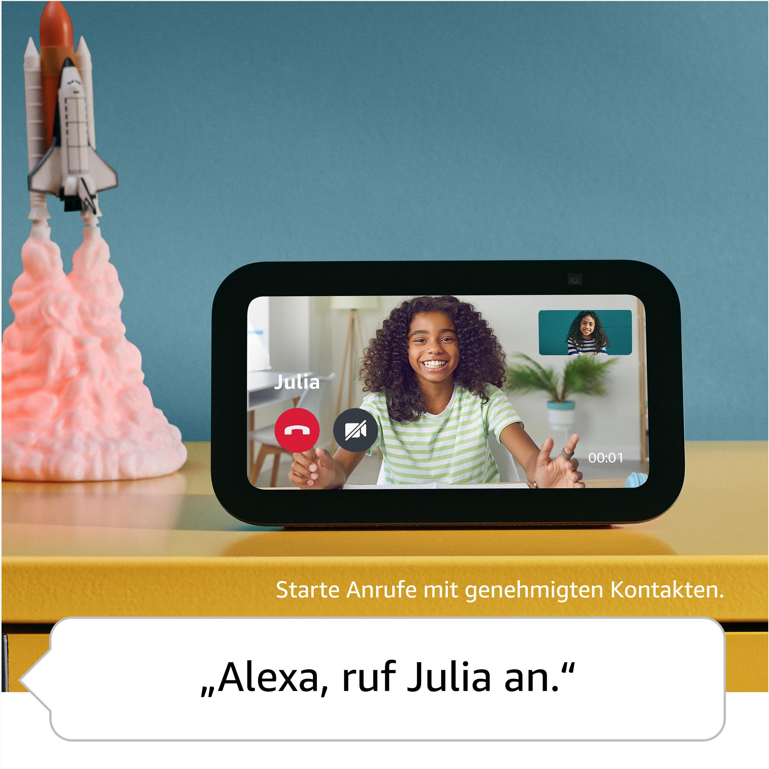 Ein Smart Display zeigt einen Videoanruf. Ein Mädchen ist auf dem Bildschirm; Sprechblase sagt: „Alexa, rufe Julia an“.