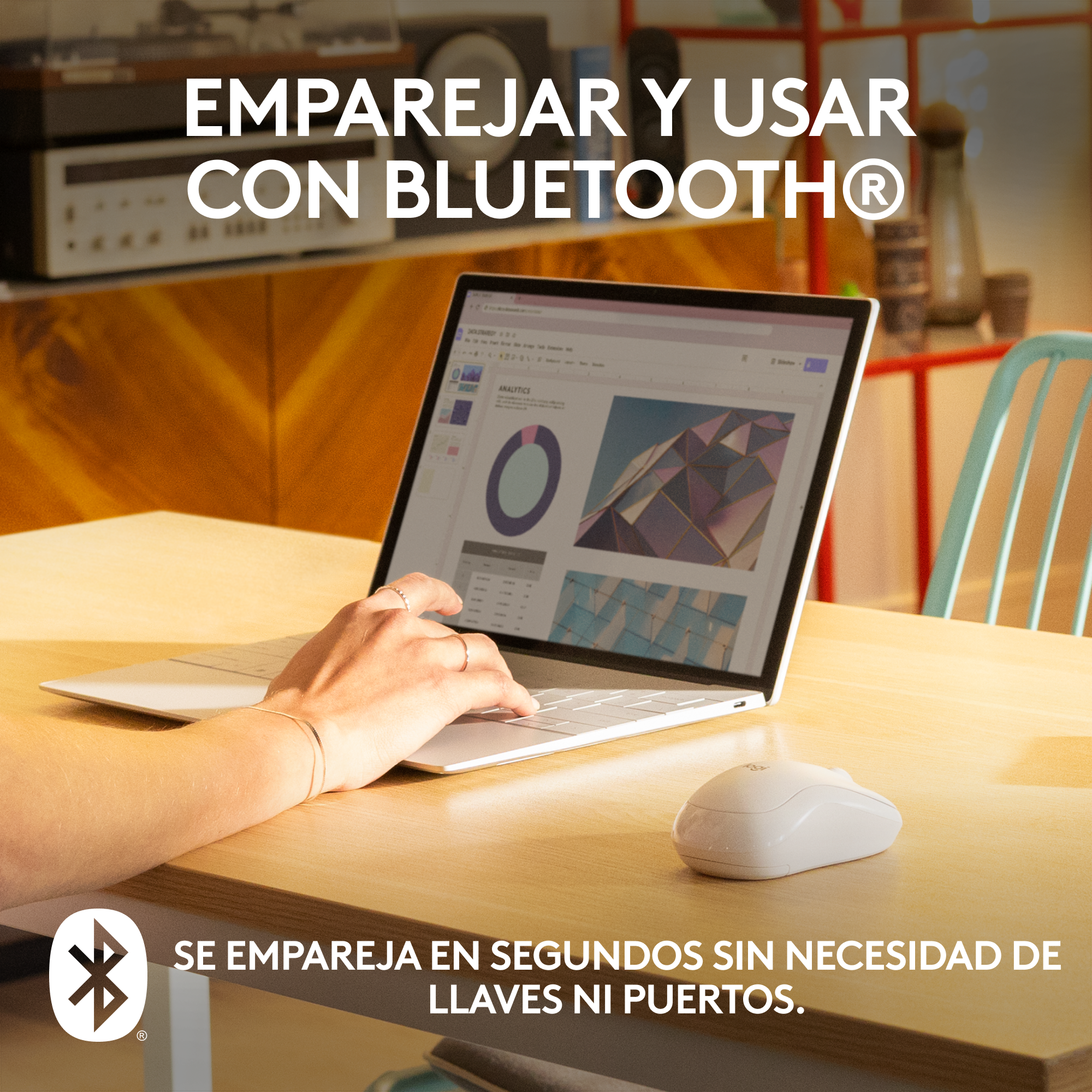 Un portátil con un ratón blanco sobre una mesa de madera. La mano de una persona está en el portátil.