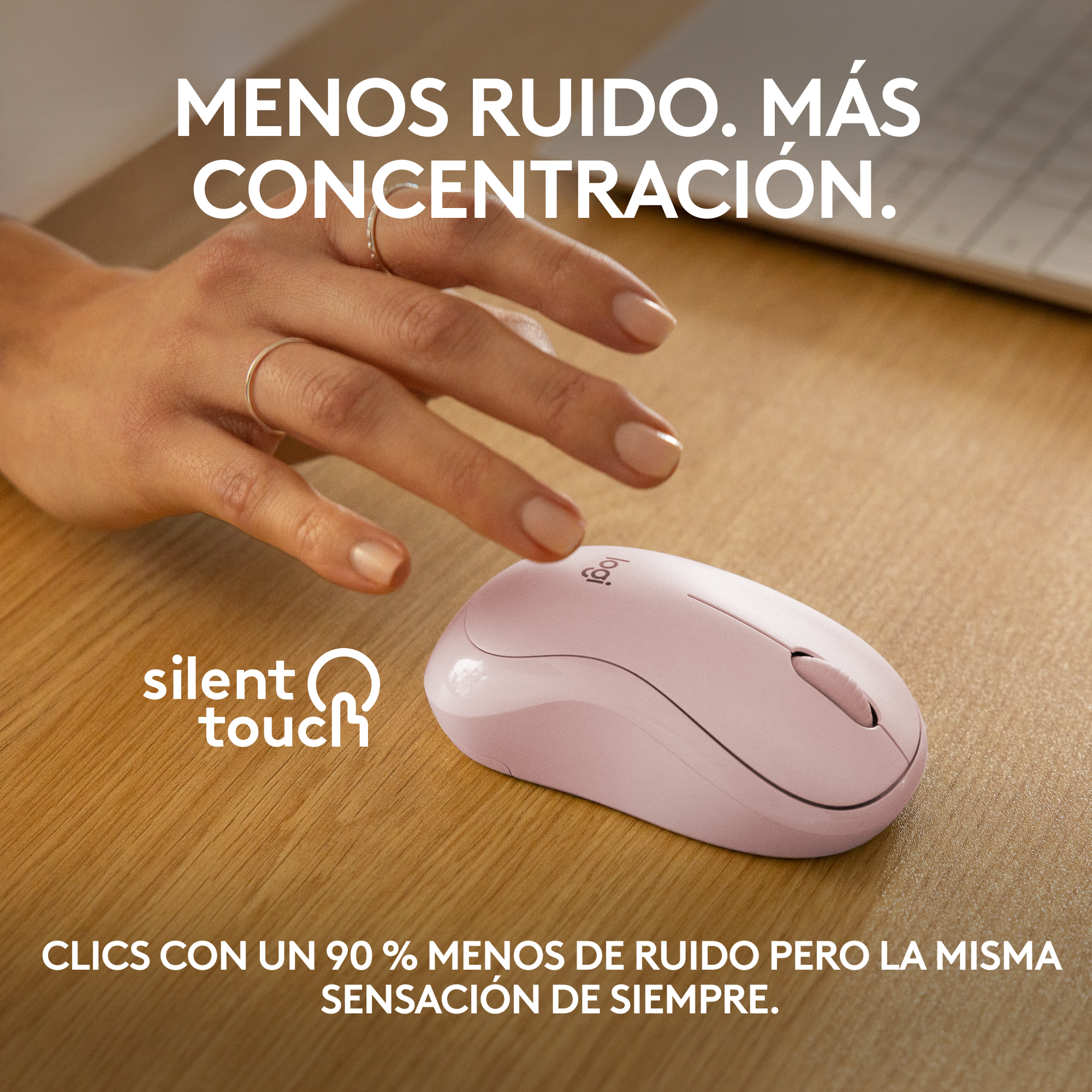 Ratón Logitech rosa con mano con anillo dorado, sobre mesa de madera con texto.