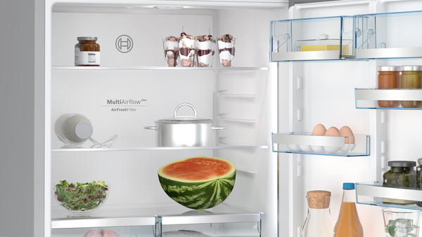 Açık buzdolabı içinde yiyecekler: karpuz, salata, kavanozlar ve kaplar.