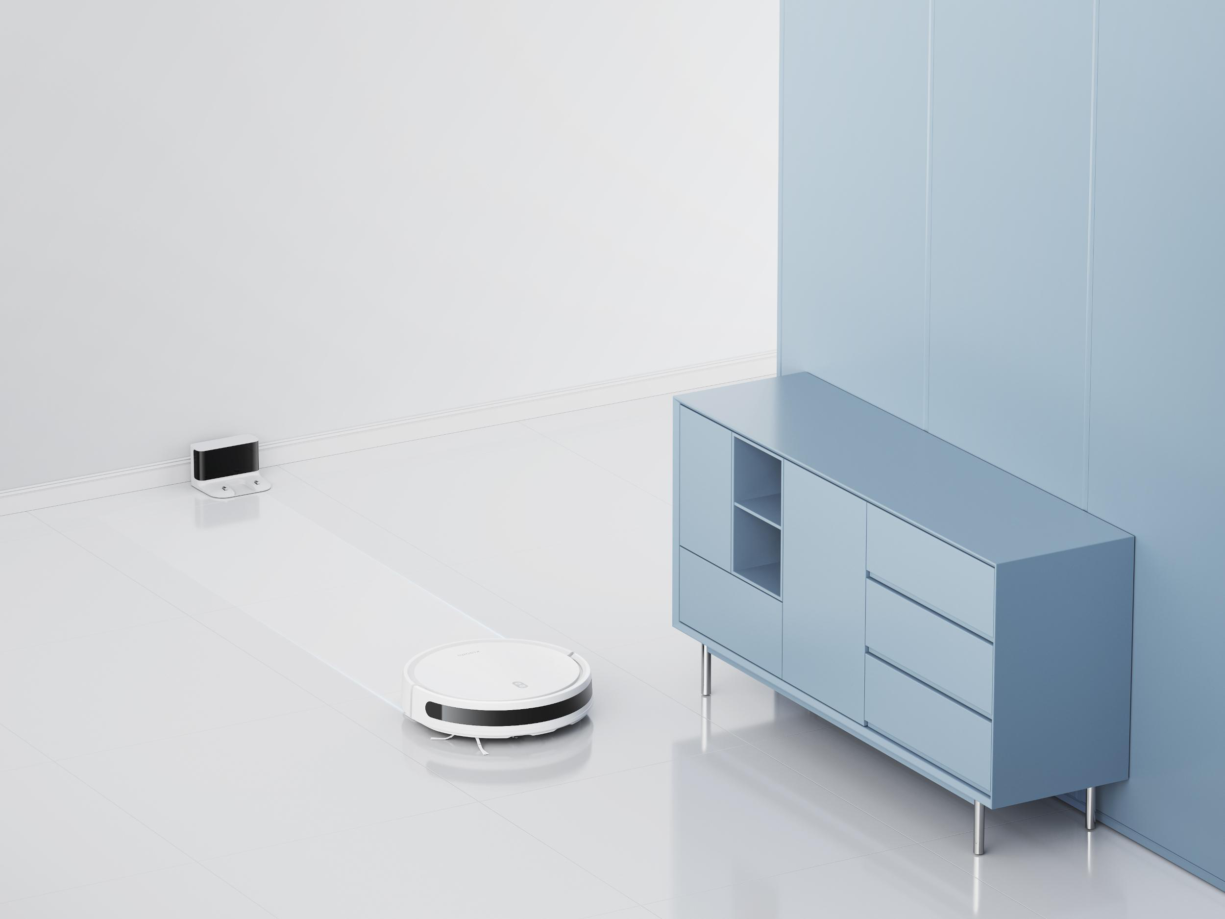 Ein Roboter-Staubsauger reinigt einen weißen Boden in der Nähe eines blauen Schranks.