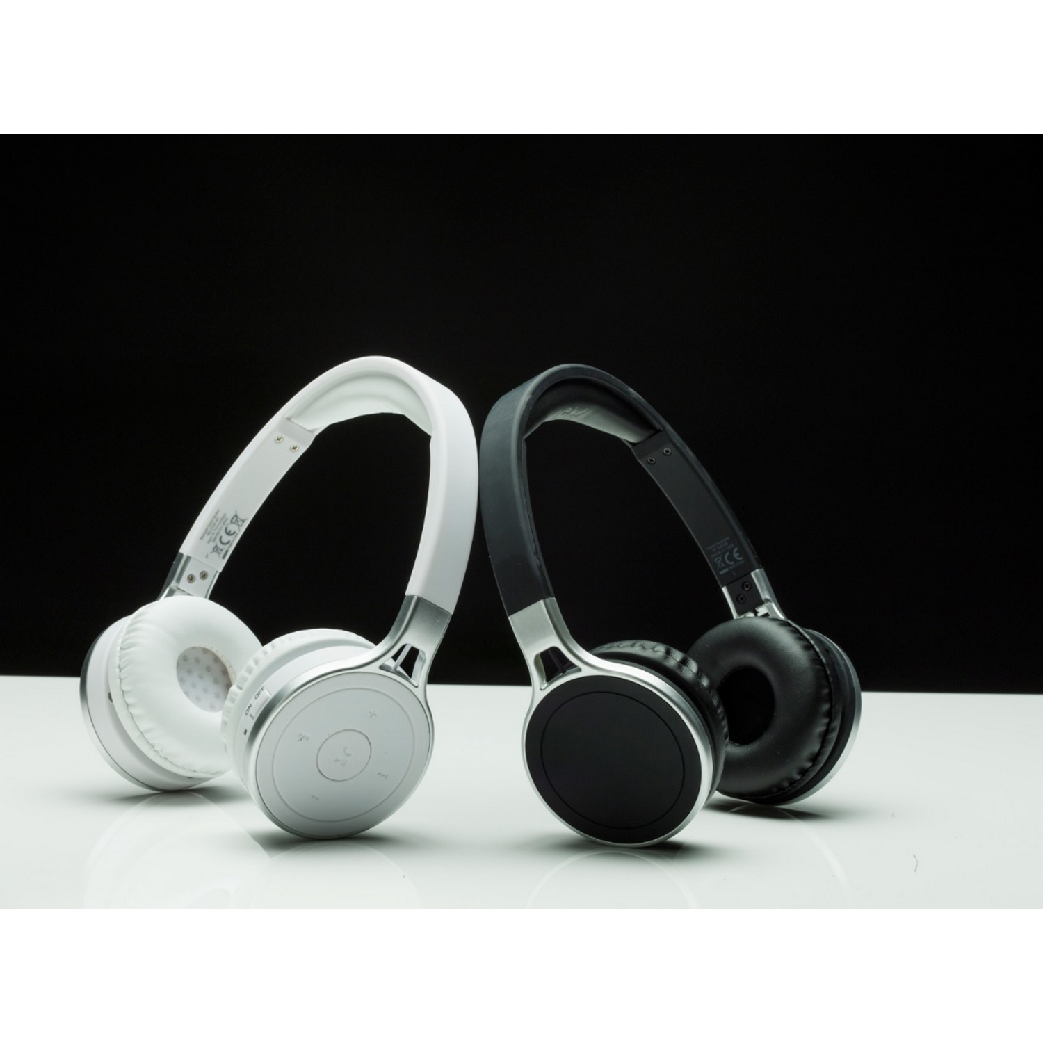 Two wireless headphones, white and black. Both have silver accents and are on a white surface.