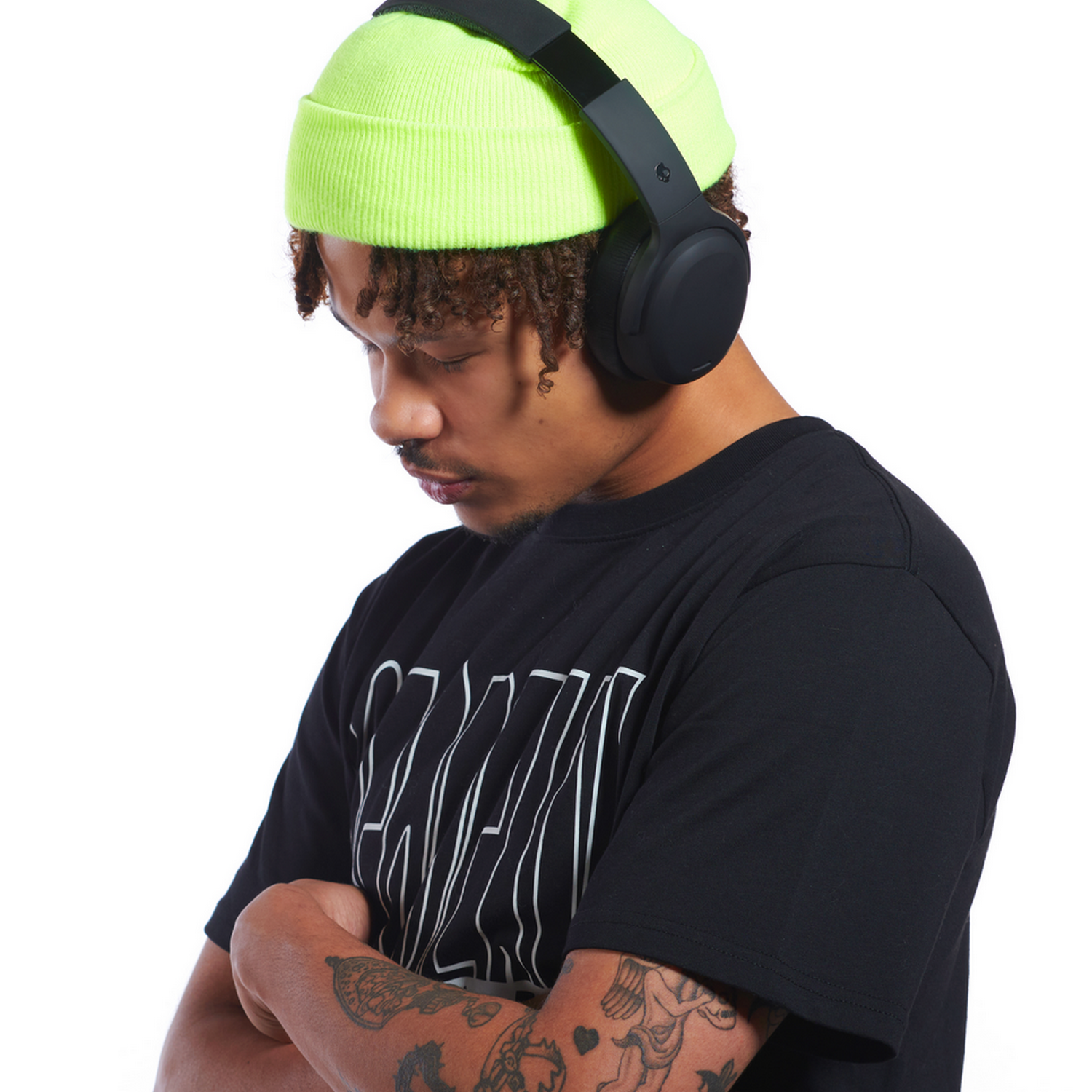 A young man wearing a neon green beanie and black headphones. He has a black t-shirt.