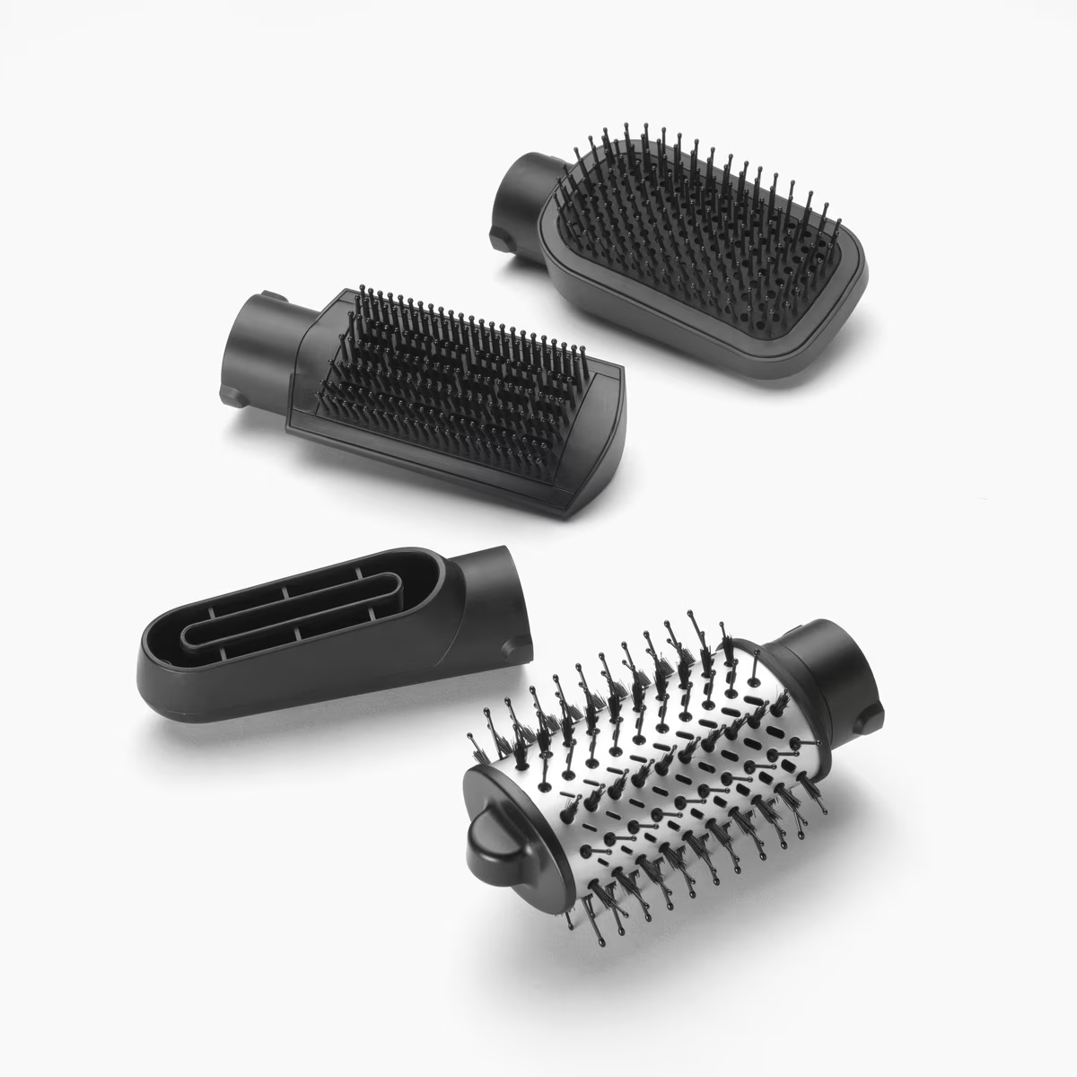 Cuatro accesorios negros para secador de pelo. Cada uno tiene un diseño diferente de cepillo o boquilla.