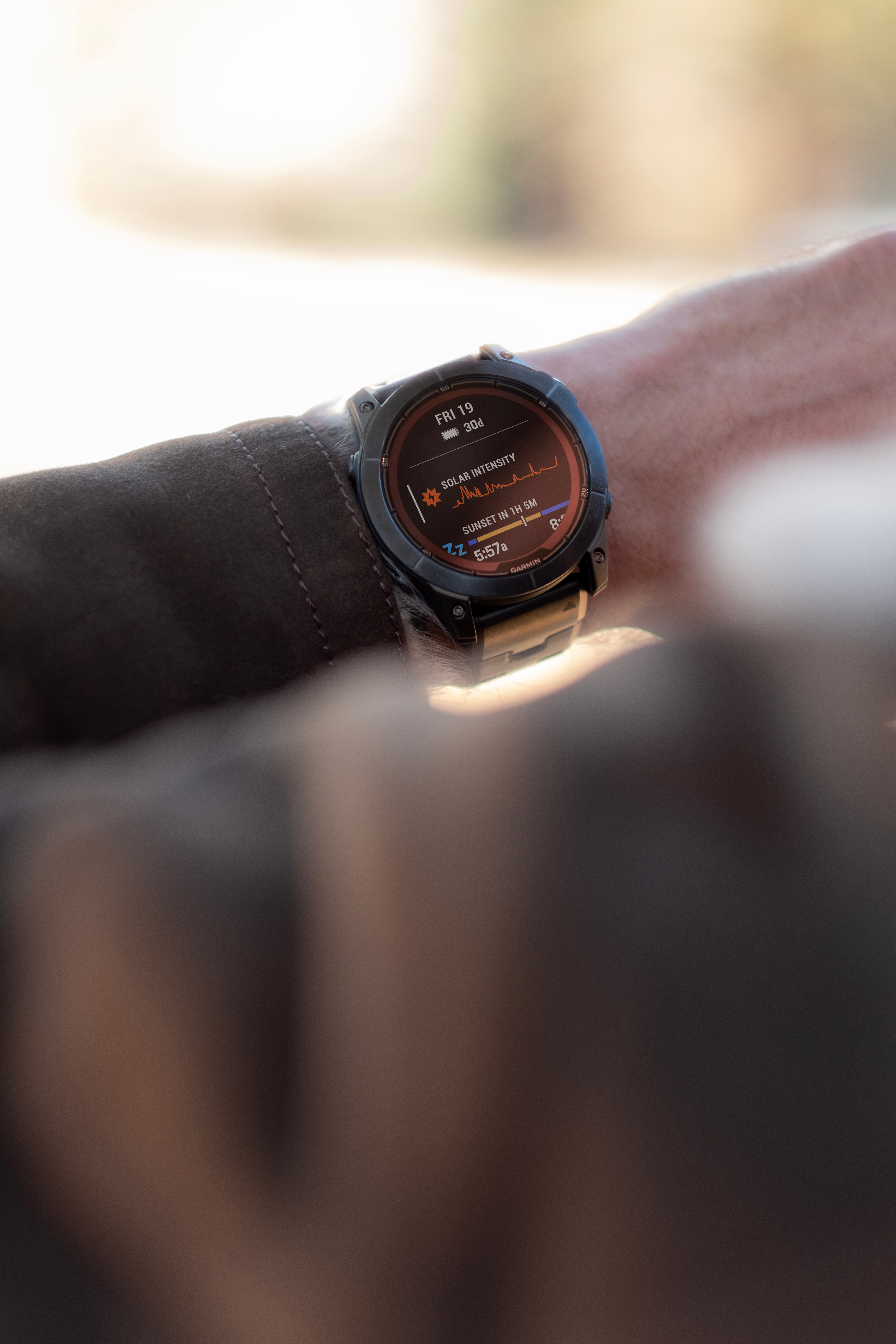 Le poignet d'une personne avec une montre connectée noire affichant l'heure, l'intensité solaire et les données de sommeil.