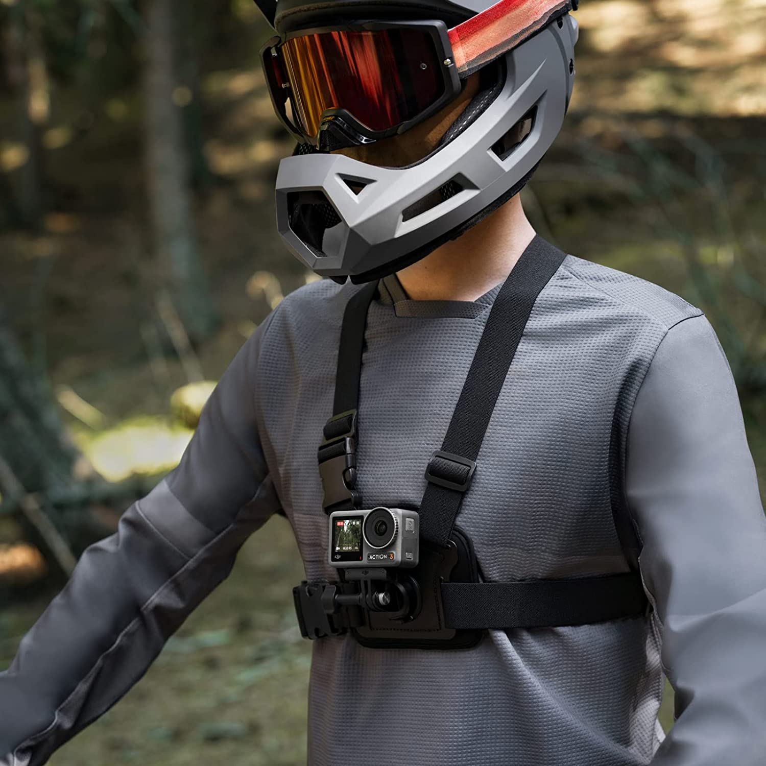 Kask ve göğüs kayışı takan, kamera takılı kişi. Orman arkaplanı.