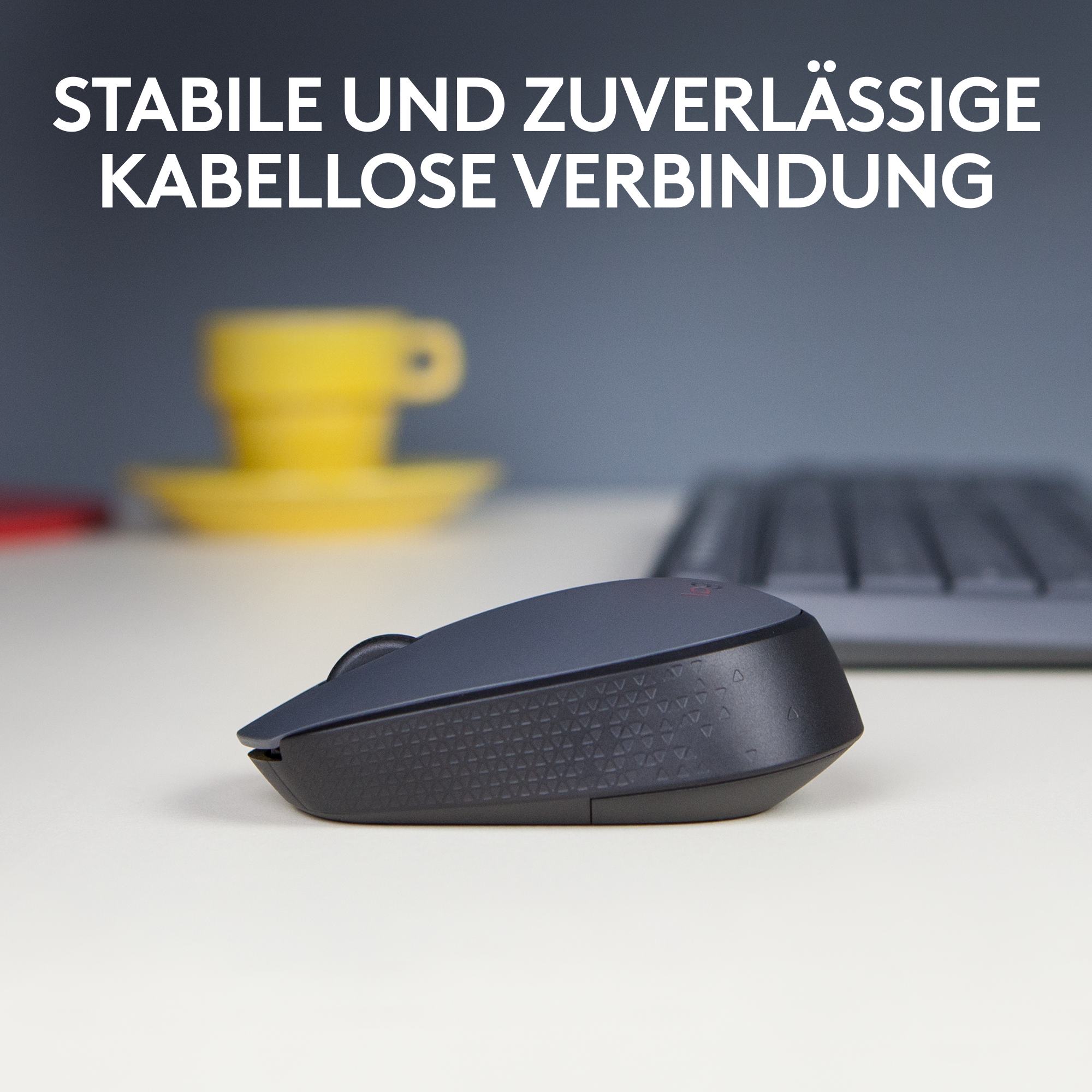 Eine schwarze Maus auf einer weißen Oberfläche. Eine Tastatur ist im Hintergrund.