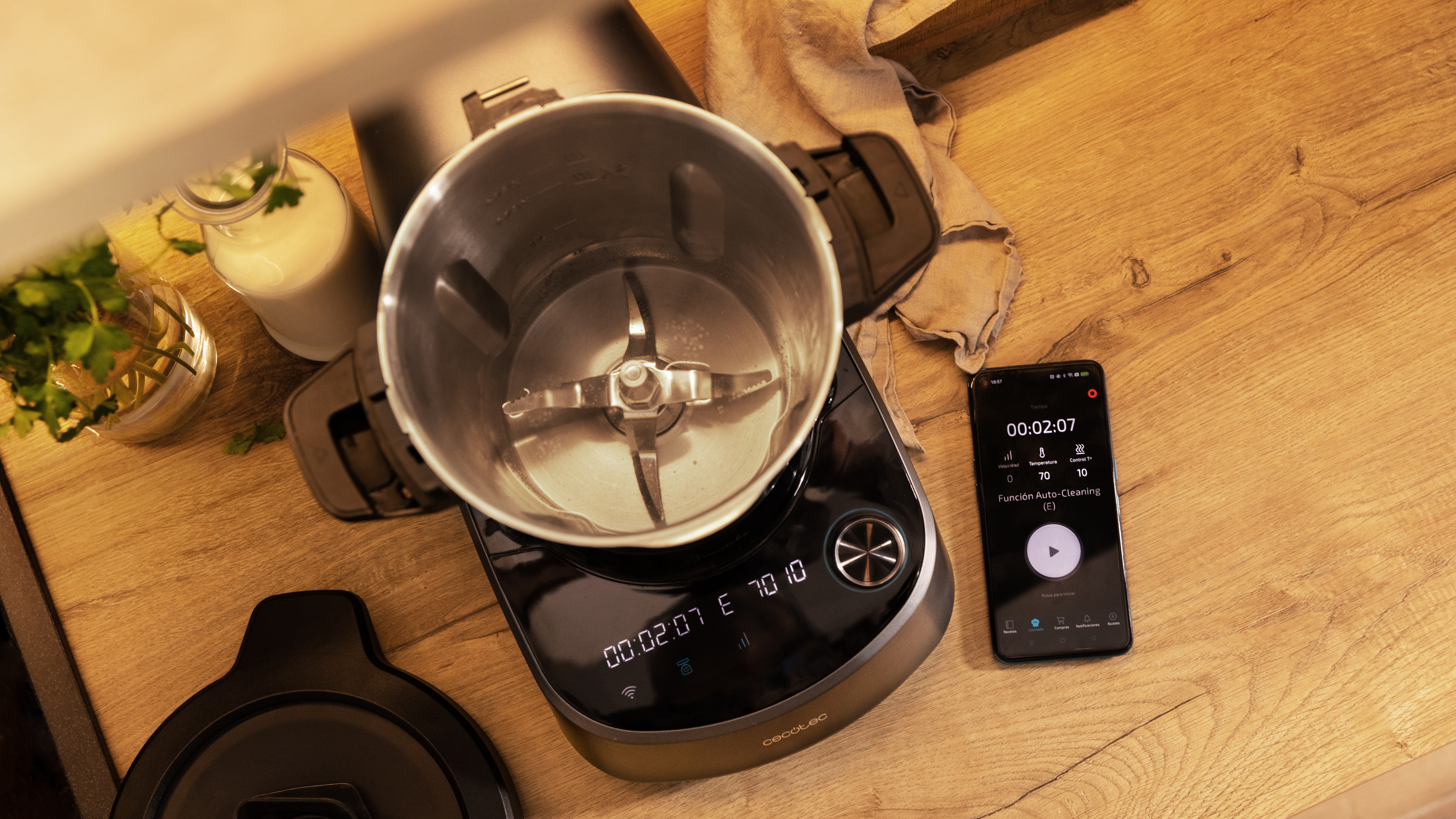 Un procesador de alimentos con temporizador y un smartphone en una superficie de madera.