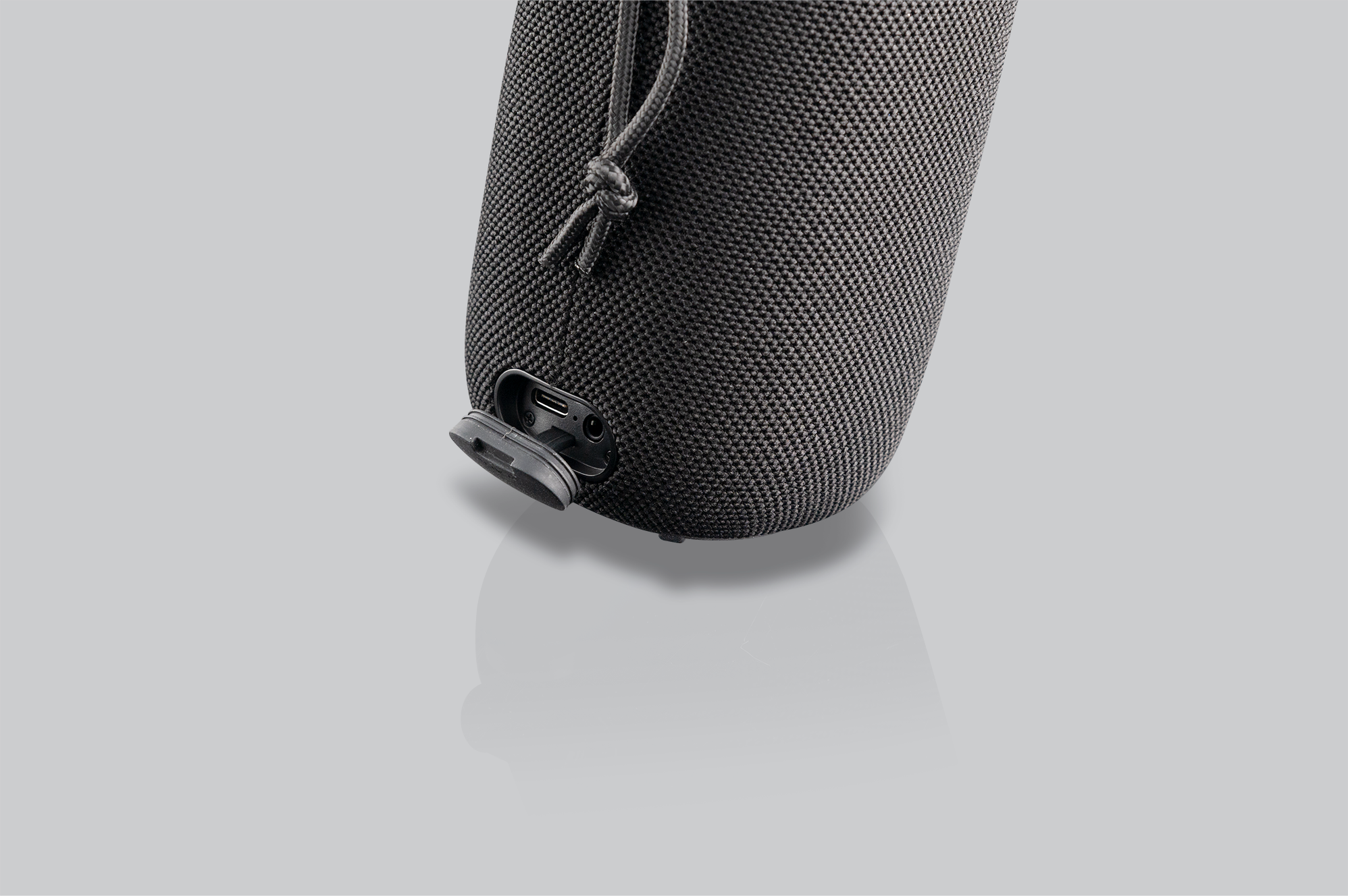 Altoparlante nero con porta USB e ingresso di alimentazione. Sfondo grigio chiaro.