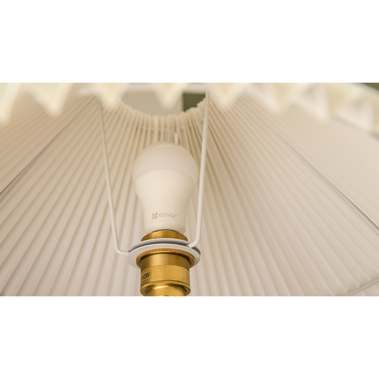 Una lampadina bianca in una lampada bianca con paralume plissettato.