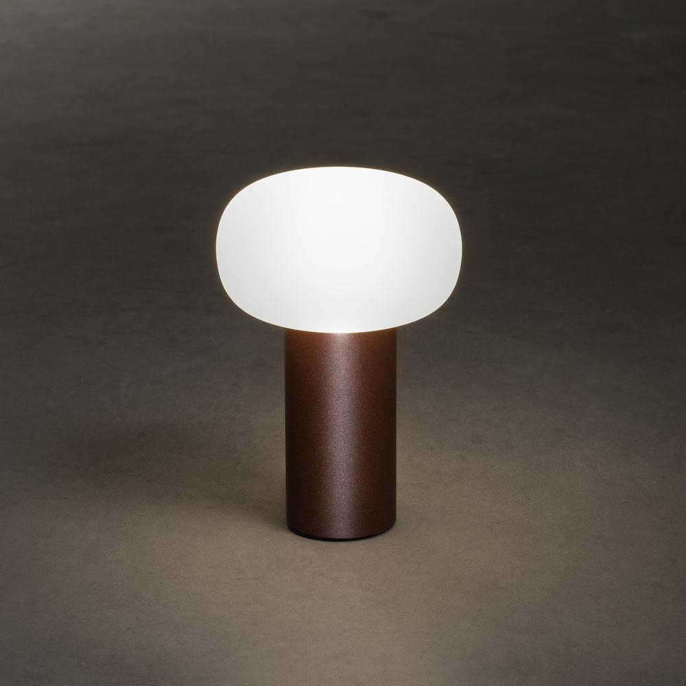 Eine kleine, braune Tischlampe mit einem weißen, oval geformten, Licht emittierenden Oberteil.