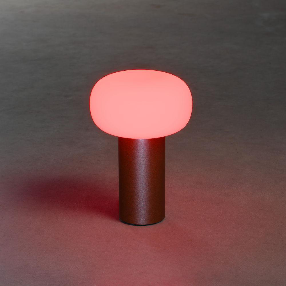 Eine kleine Tischlampe mit braunem Sockel und rotem, ovalförmigem Licht.