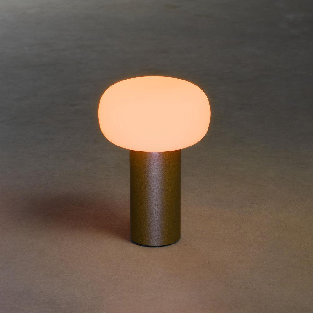 Kleine Tischlampe mit rundem, orangefarbenem Licht auf goldfarbenem Sockel.