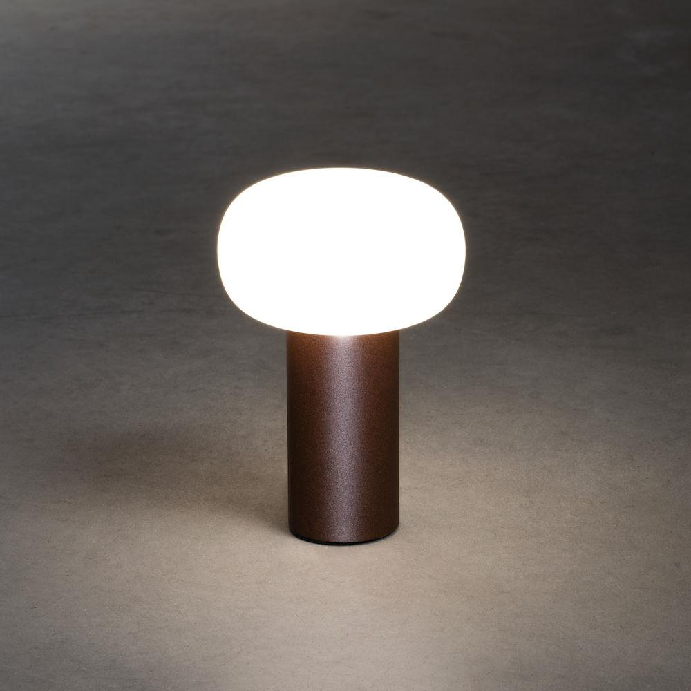Eine braune Tischlampe mit zylindrischem Sockel und ovalem, weiß leuchtendem Licht obenauf.