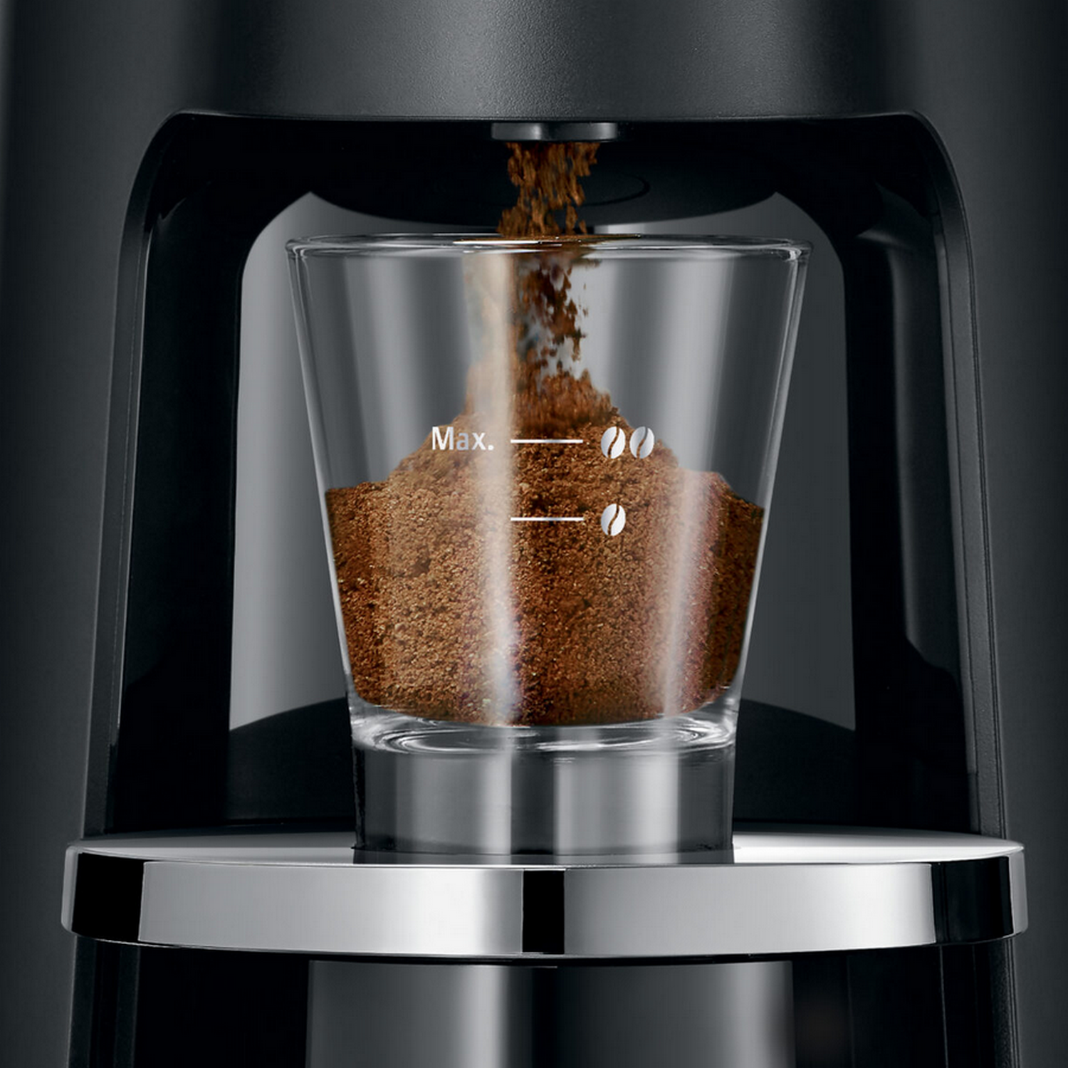 Coffee grounds falling into a clear glass with 'Max.' marked on it.